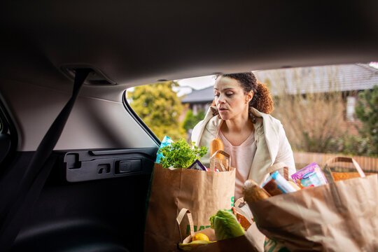 Woman taking groceries out of car trunk
