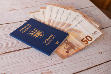 Ukraine passport for traveling in Europe against the background of Euro banknotes and wood. Concept on the theme of travel on low-cost aircraft. receiving benefits for refugees from Ukraine