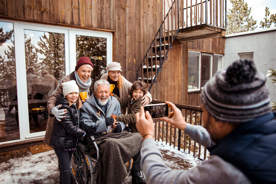 Multi-generational family taking a group photo outside in winter with snow