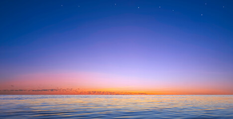 Fototapeta premium Beautiful twilight sky background over sea and stars on colorful evening sky with light reflection on water surface, Idyllic natural tranquil seascape view