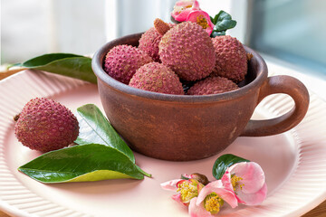 Lychee fruits in rustic ceramic teacup. Litchi Sonn. Flowers of Japanese quince. Tropical fruits....