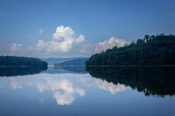 Blue lake and sky with clouds, reflection in the water, Bieszczady, Lake Solina, Poland. Late summer.
