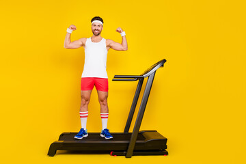 Full body portrait of muscular handsome man stand treadmill flexing biceps empty space isolated on...