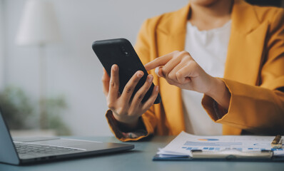 Asian businesswoman in formal suit in office happy and cheerful during using smartphone and working