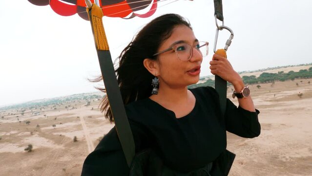 4K portrait of young Indian woman travel vlogger vlogging while flying in Parasailing over Thar desert in Rajasthan, India. Social media influencer on historical location in India. Confident and happy