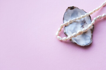 Necklace made of natural pearls on a pastel pink background.