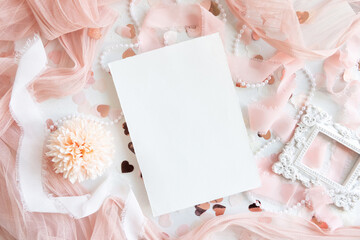 Vertical card near pink decorations, hearts and silk ribbons on white table top view, mockup