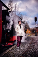 Obraz premium Thoughtful Young Person by Historic Steam Train on Cobblestone Platform