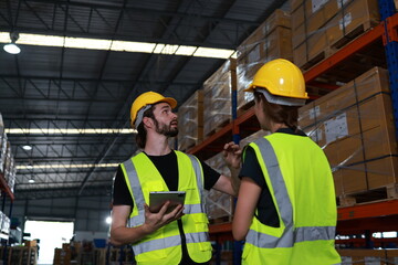 Two distribution warehouse coworkers are walking using a digital tablet to check inventory on a physical count