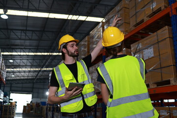Two distribution warehouse coworkers are walking using a digital tablet to check inventory on a physical count