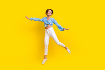 Fototapeta na wymiar Full size photo of elegant dreamy girlish woman wear print blouse flying hold hands like wings isolated on yellow color background