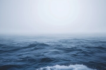 Fototapeta premium A large body of water with powerful waves crashing in the foreground of a sweeping coastal landscape, Atmospheric representation of a foggy ocean with barely visible waves, AI Generated