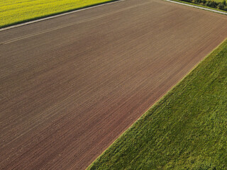 View from above of farm fields with soil and grass in the countryside 