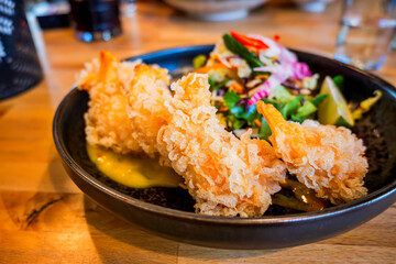Fried tempura shrimp, mango sauce, salad in bowl on table.
