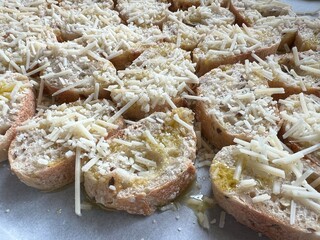 Baked sliced baguette drizzle with olive oil topped with parmigiano reggiano cheese