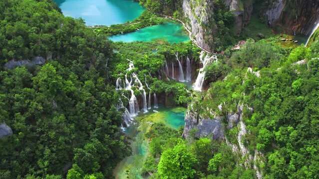 Mountain waterfall flows into a lake with many streams of water. Green summer forest in Plitvice National Park Croatia.