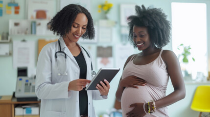 smiling pregnant woman is looking at a tablet screen shown to her by a healthcare professional in a medical office setting.