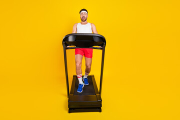Full length photo of impressed shocked guy sportswear running fast falling treadmill empty space isolated yellow color background - obrazy, fototapety, plakaty