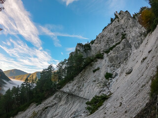 Scenic view of fog covered valley in Hochschwab mountain range, Styria, Austria. Hiking trail in alpine forest. Remote Austrian Alps in summer. Escapism. Connect with nature