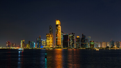 Fototapeta na wymiar Amazing night city of Abu Dhabi. Cityscape by the water at night. Technology and the modern city