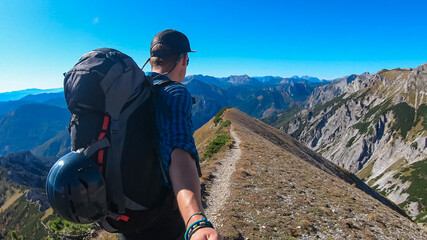 Hiker man on idyllic hiking trail on alpine meadow with scenic view of majestic Hochschwab mountain...