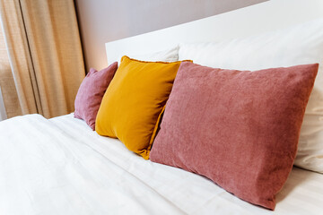 A bed with white linens and vibrant throw pillows, offering comfort in a bedroom