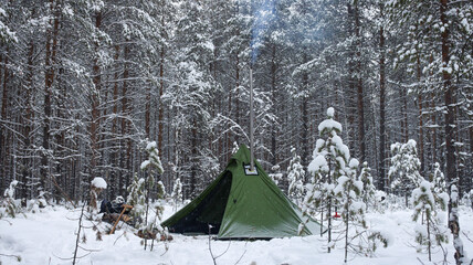 Winter camping in the Boreal Forest. Hot tent. Tipi stands in the winter forest. Tepee in the snow. Ecotourism