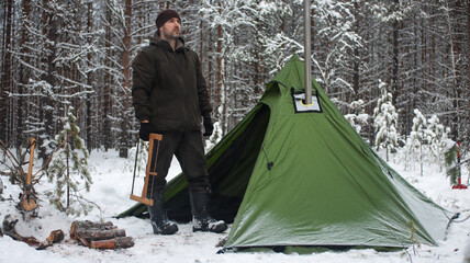 Winter camping in the Boreal Forest. Hot tent. Man stands by a tent. Tepee in the snow. Ecotourism