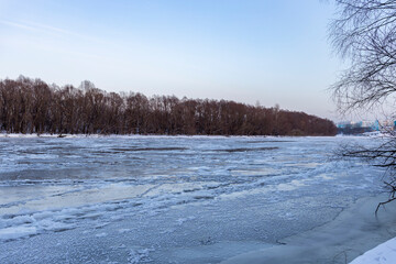 Ice floats on the water, frosty evening, cold, winter landscape with a wide river.