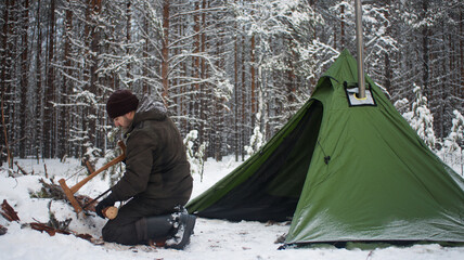Winter camping in the Boreal Forest. Hot tent. Man stands by a tent. Tepee in the snow. Ecotourism