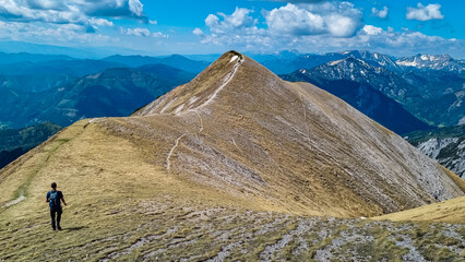 Hiker man on idyllic hiking trail on alpine meadow with scenic view of majestic Hochschwab mountain...