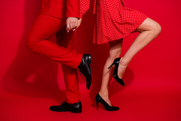 Cropped photo of two partners hold hands legs luxury footwear isolated on bright red color background