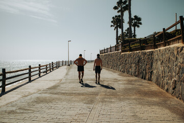 Turyści spacerują promenadą w słoneczny dzień, Bahia Feliz, Gran Canaria, Hiszpania - obrazy, fototapety, plakaty