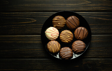 Round cookies with white and dark chocolate or chocolate brownie on a black plate. Delicious...