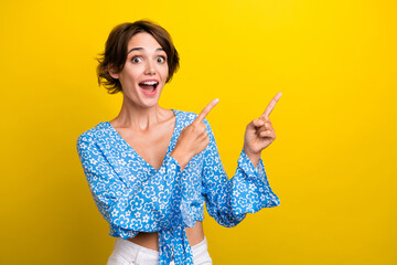 Photo of adorable excited young woman wear print blouse open mouth pointing two fingers empty space...