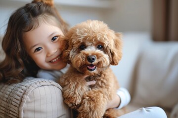 A young girl sits indoors, beaming with joy as she poses with her beloved poodle crossbreed, a playful and loyal companion