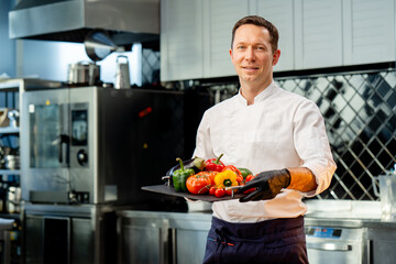 chef holding a tray with different washed vegetables ready use colorful vegetables in the kitchen