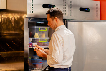 professional kitchen chef looks into the fridge and chooses ingredients for cooking food concept