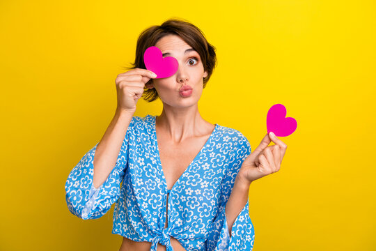 Photo of flirty funky woman wear flower print blouse sending you kiss pink heart close eye isolated yellow color background