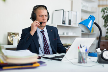 Call center man operator with headset talking with client in agency