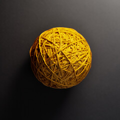 Closeup of a spherical object created from yellow elastic bands on a dark backdrop