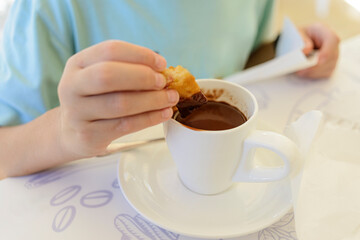 Hand dipping a churro in chocolate.