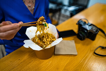 Woman eating noodles with vegetables and meat from Chinese.