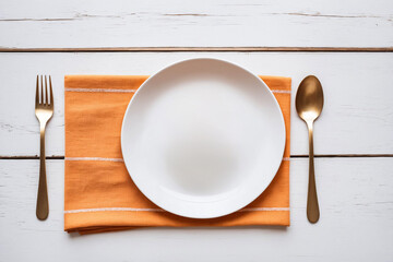 Orange linen on rustic white slat wood surface, small white plate, golden fork and spoon, shot overhead, top view. Food or dessert presentation background, banner, empty, template, backdrop.