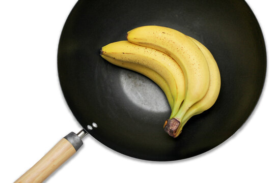 Bananas on frying pan. Bunch of bananas. Conceptual background of frying bananas. Unpeeled bananas. Yellow fruit with brown spots. Over ripe brown banana in deep WOK isolated on white cutout.