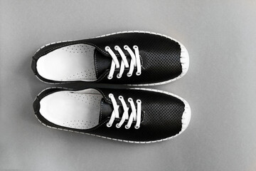 Stylish black leather sneakers on a gray background, close-up.