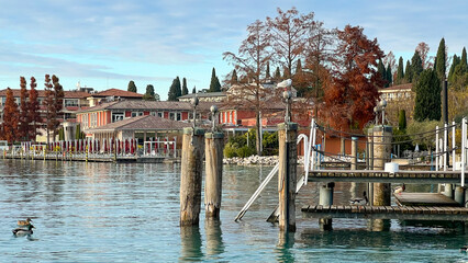 View of Lake Garda with turquoise water and wooden pier at sunset. City of Sirmione, Lombardy,...