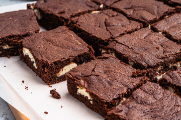 Chocolate brownie cake with cream cheese on wooden board, close up