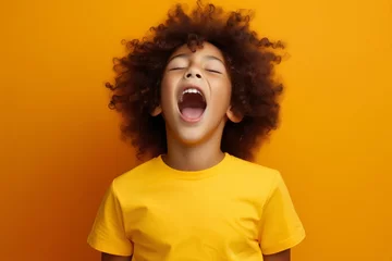 Fotobehang extremely whim Upset black curly haired boy in t shirt screaming and crying or very emotional expression sings songs with opened mouth and closed eyes against orange color wall © useful pictures