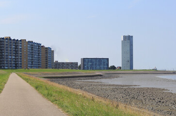the boulevard of the port city Terneuzen with flats and a residential tower behind the seawall of the westerschelde sea
